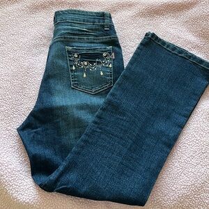 Dark wash jeans with embellished pockets.